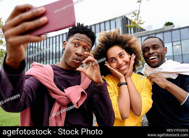 Young man taking selfie with friends on mobile phone