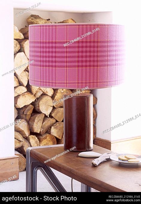 Lamp on wooden coffee table with large pink patterned shade and leather base
