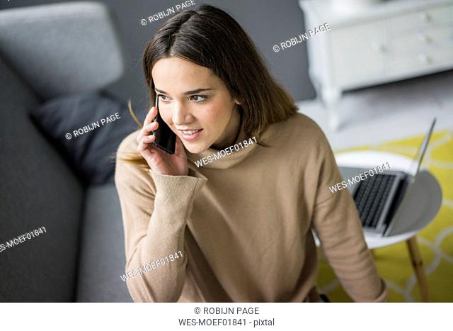 Portrait of smiling woman on the phone at home