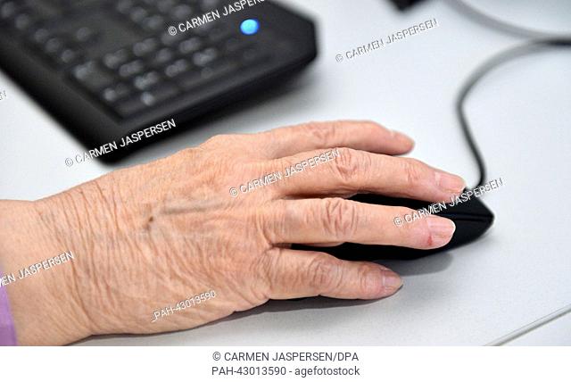 The hand of senior citizenoperates on a computer mouse on a desktop computer at the internet cafe for senior citizens at the adult education centre in Vechta