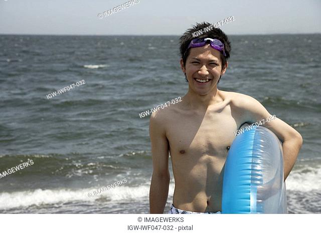 Portrait of a young man on beach with a lifebuoy