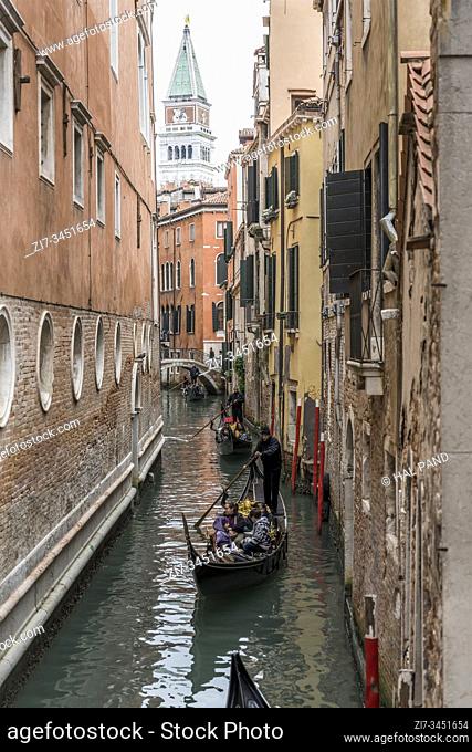 VENICE, ITALY - October 30 2019: cityscape with gondolas in narrow canal with s. Marco bell tower looming in background, shot on october 30 2019 in bright...