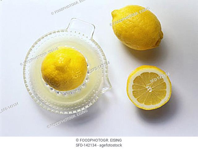 Lemon half on squeezer, with lemon & lemon half beside it