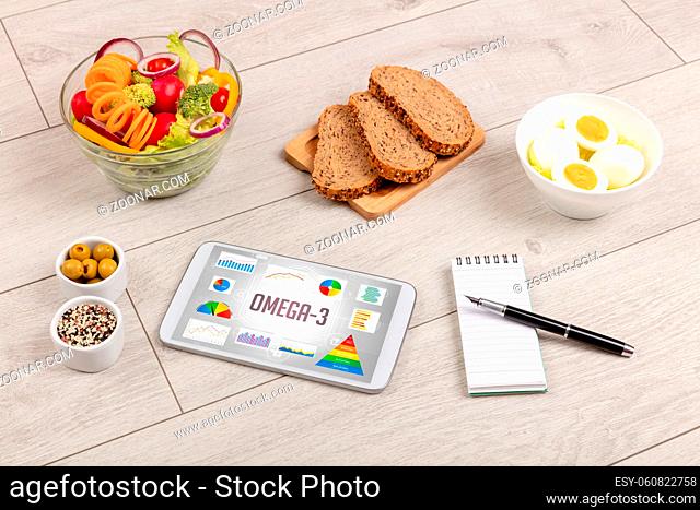 Organic food and tablet pc showing OMEGA-3 inscription, healthy nutrition composition