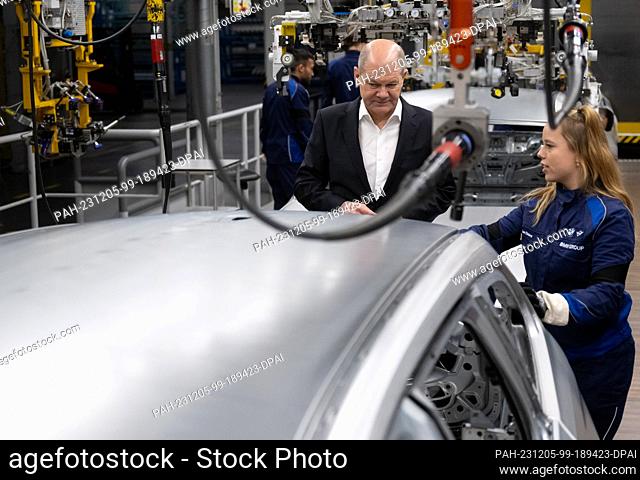 05 December 2023, Bavaria, Munich: Federal Chancellor Olaf Scholz (SPD) takes part in a tour of the BMW plant and is shown around production by an employee