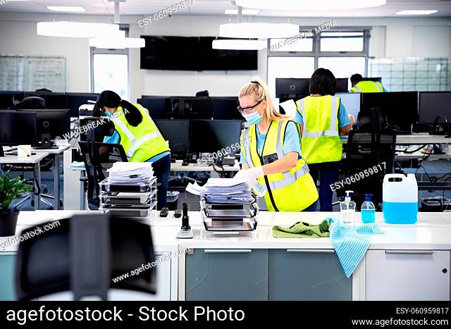 Caucasian woman and colleagues wearing hi vis vests, gloves, safety glasses and face masks sanitizin