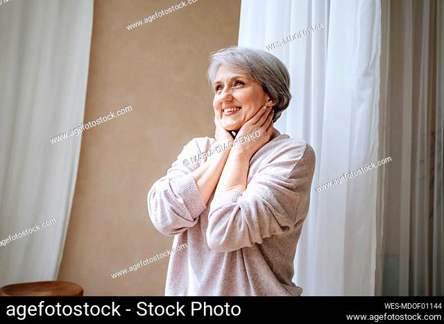 Smiling mature woman day dreaming at home
