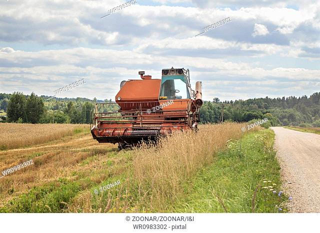 Old harvester on the field near road