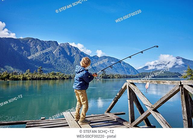 Chile, Chaiten, Lago Rosselot, boy standing on jetty fishing in lake
