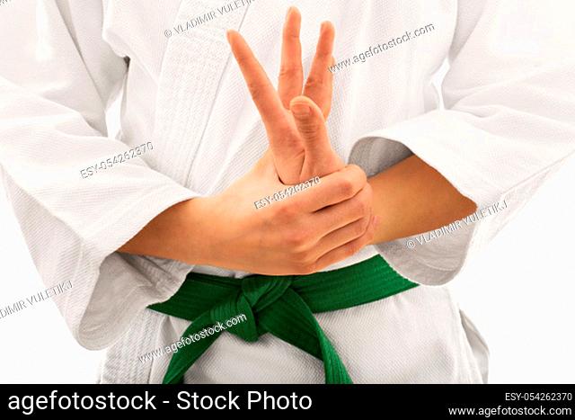 Close up shot of the mid section of a martial arts fighter in white kimono with green belt stretching and twisting her hand, isolated on white background