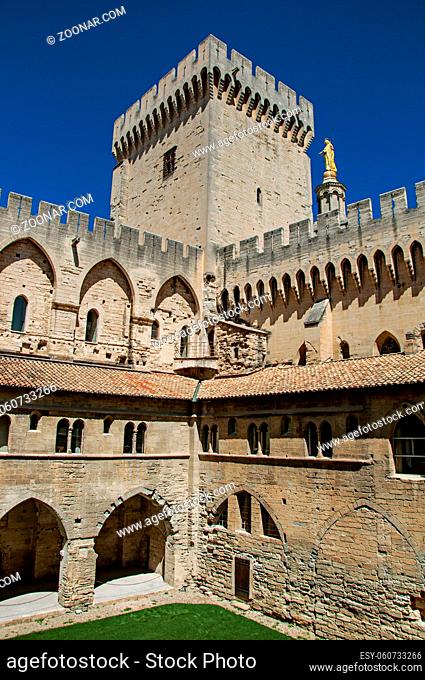 View of courtyard and internal buildings at the Palace of the Popes of Avignon, under a sunny blue sky. Located in the Vaucluse department