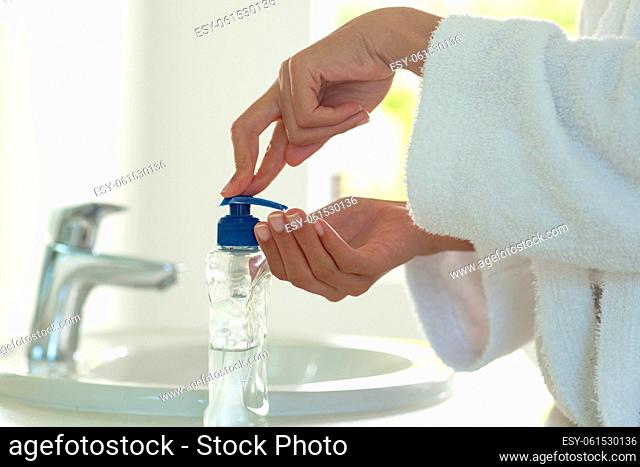 Mixed race woman wearing bathrobe and washing hands in bathroom