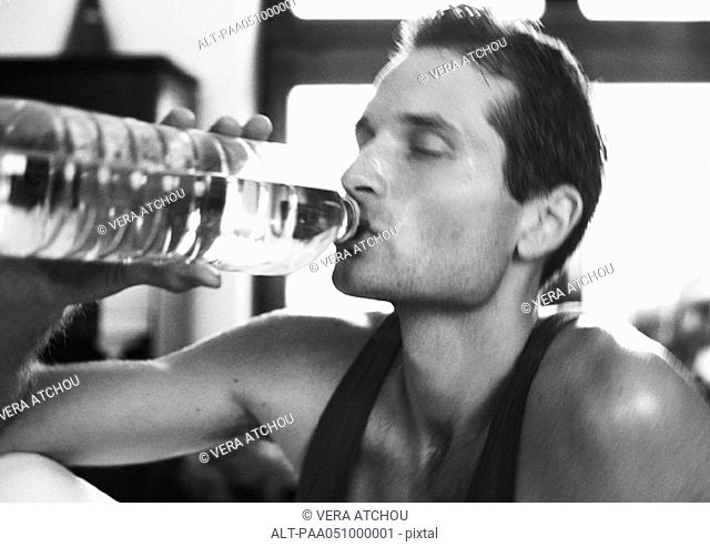 Man drinking from bottle, close-up, b&w
