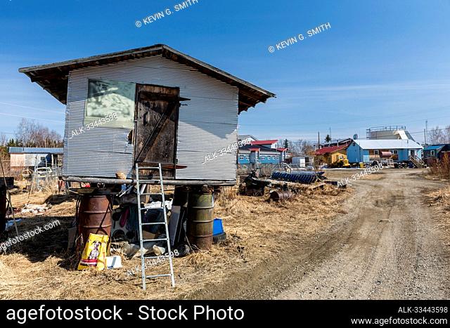 Corrugated metal storage shed elevated on pilings and repurposed 55 gallon oil drums to keep from being flooded, Kobuk, Northwestern Alaska, USA; Kobuk, Alaska