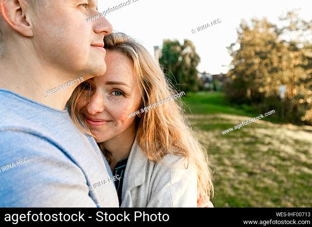 Blond woman embracing boyfriend in park