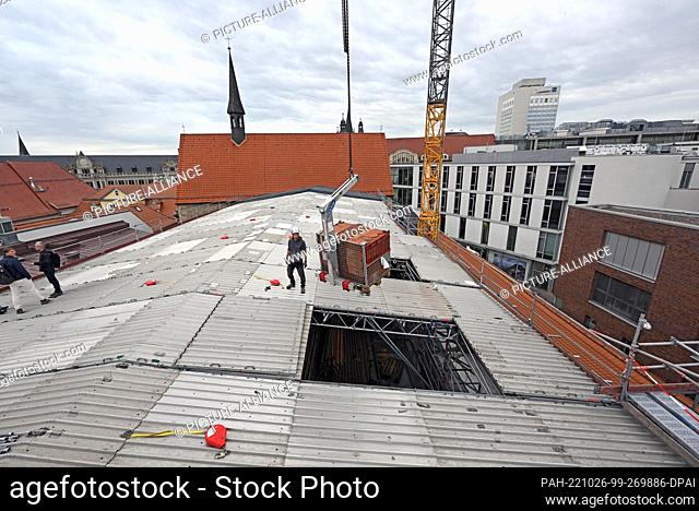 26 October 2022, Thuringia, Erfurt: Craftsmen work on the weather protection roof above the roof of the old convent building in the Ursuline Convent