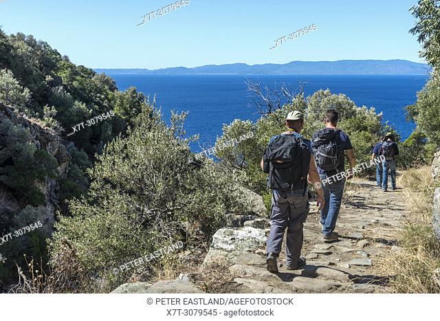 Walkers on a path between Xeropotamou and St. Panteleimon monasteries on The Southwest coast of the Athos peninsula, Macedonia, Northern Greece