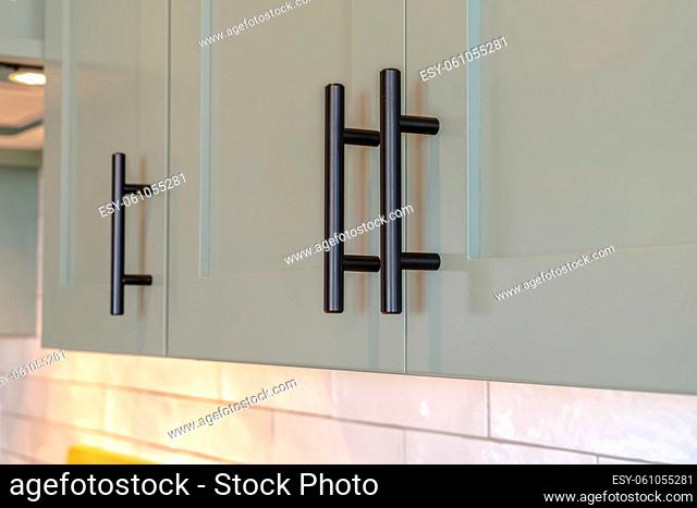 Close up of overhead kitchen cupboards and handles. A close up of overhead kitchen cupboards with black handles
