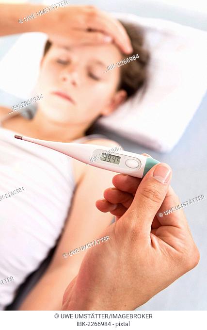 Digital fever thermometer showing the high temperature of a young girl with fever