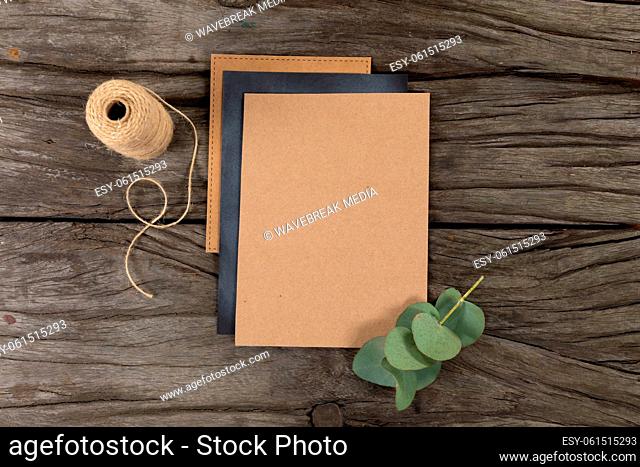 Notebook and black sheet of paper surrounded by a flower and knitting yarn on wood table