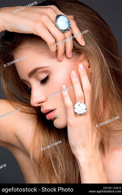 Beautiful young woman with perfect skin, loose hair and white rings on fingers. Beauty shot. Over background