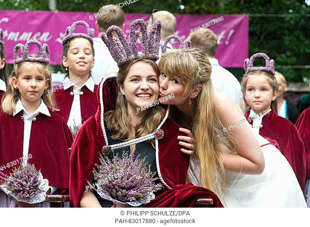18-year-old Marie-Louisa Sebastian (m) receives a kiss from her predecessor Victoria Glaser (r) after her election as the new heather queen in Amelinghausen