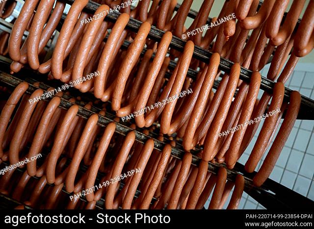 14 July 2022, Saxony-Anhalt, Halberstadt: Freshly smoked sausages from the chimney smoke chamber are ready for cooling and further processing