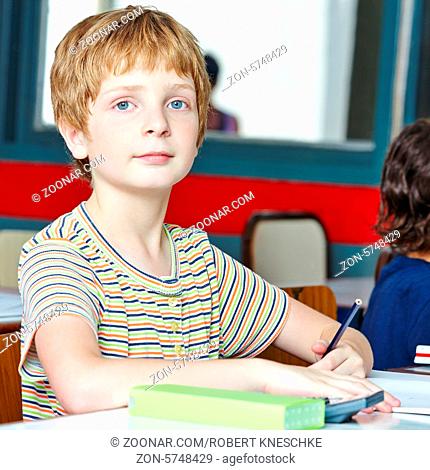 Kind sitzt im Unterricht in Grundschule und schreibt linkshändisch