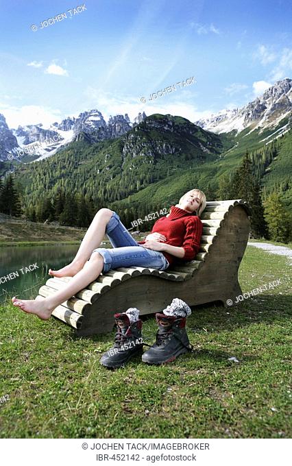 AUT, Austria, Fulpmes, Stubai Valley: Hiking path in the mountains to the Schlickeralm. Relaxing at the Speichersee lake on wooden chairs and beds. |