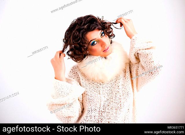 Beautyfull young girl with dark curly hair and a make-up in peacock-colour wearing a white pullover