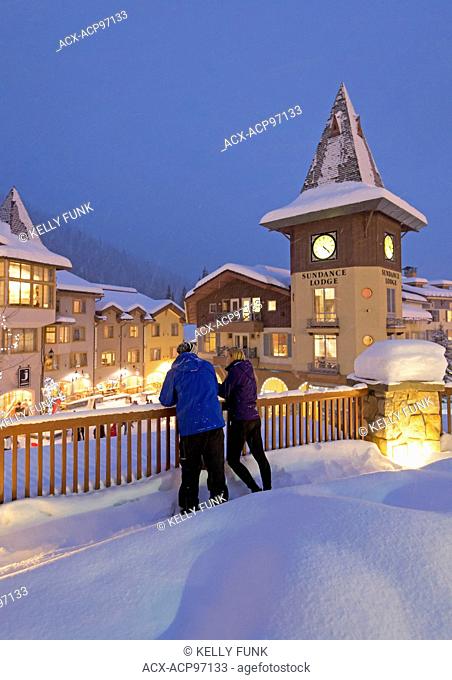 A young couple enjoys a snowy evening in the village of Sun Peaks, Thompson Okangan region, British Columbia, Canada