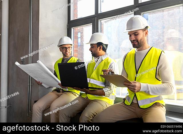 male architects in helmets with laptop at office