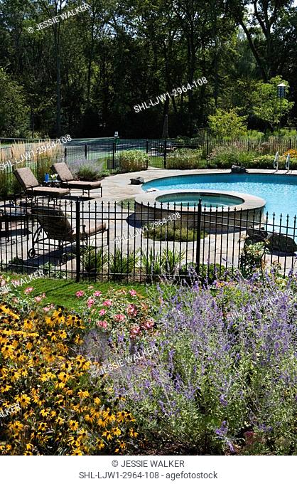 SWIMMING POOLS:Flower bed of Russian sage, brown eyed susans, roses in foreground , fenced pool area with hot tub, chaise lounges , tennis court beyond