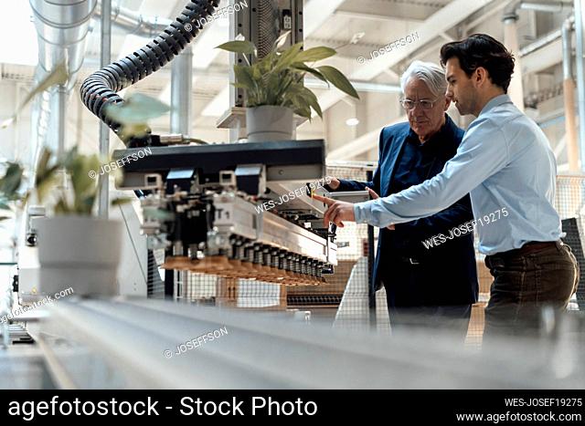 Young man discussing with colleague over machinery in industry