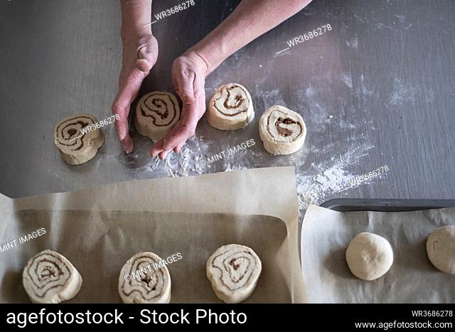 High angle close up of person shaping dough for Cinnamon Rolls on metal surface