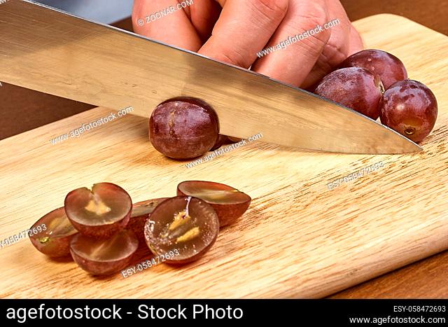 Chef-cook sliced grapes on a cutting board. Cutting ingredients closeup