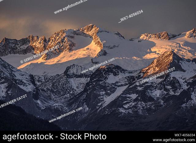 Reddish sunrise over the snowy Maladetas massif and the Aneto peak. Seen from the Varradòs Valley in autumn (Aran Valley, Catalonia, Spain)