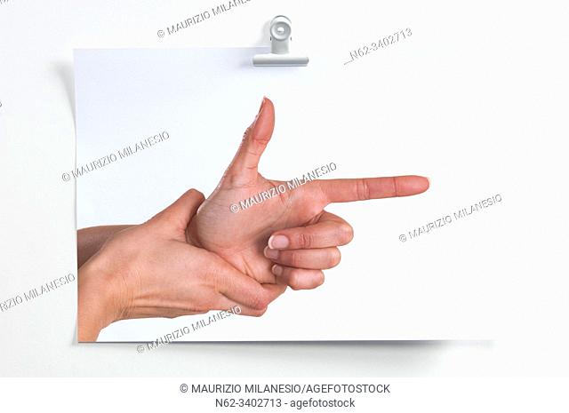 Blank sheet hanging on the wall with image of hands simulating a gun that shoots