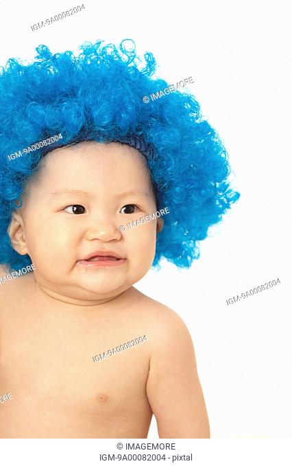 Baby girl wearing blue wig and looking away with smile