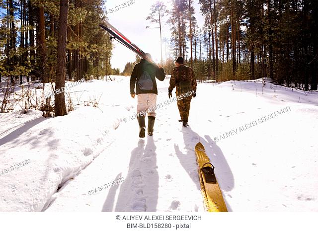 Men carrying skis on snowy path