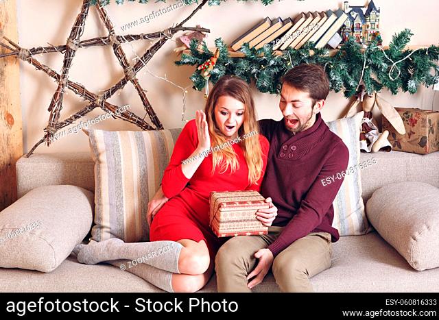 couple love in shock. Happy smiling and wondering unwrapping christmas present from her handsome boyfriend, gift card concept