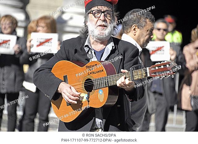 An unidentified man plays a guitar with the words ""Freedom for Catalunya"" written on it, on the street in front of the Palau de la Generalitat de Catalunya as...