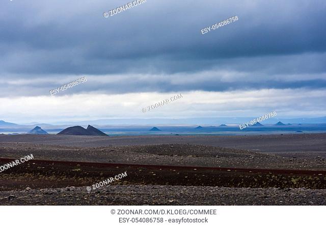 Volcanic landscape on Iceland with mountains, lava and black sand and dark rain clouds in the sky