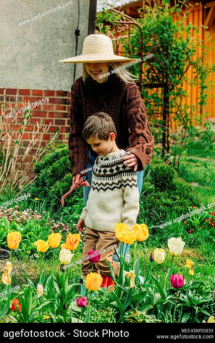 Mother and son standing near tulips in garden