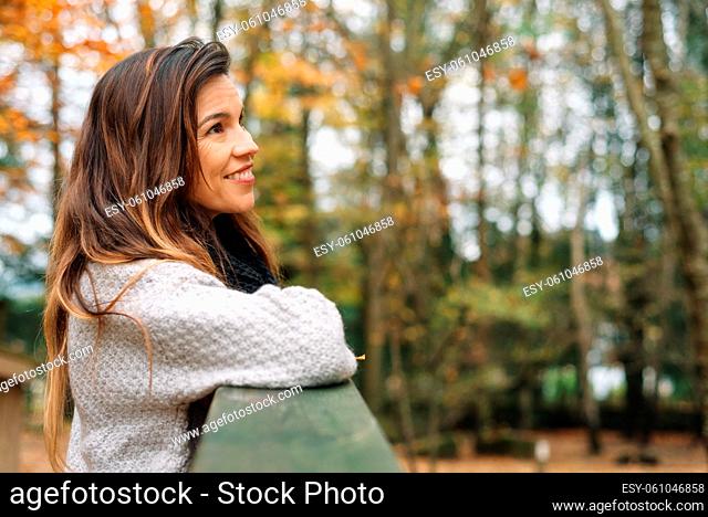 Attractive woman, relaxed in a park In autumn surrounded by colorful leaves looking to the trees pensively