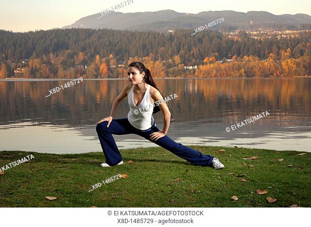 A young athletic woman stretching her legs, Inlet Park, Port Moody, British Columbia, Canada