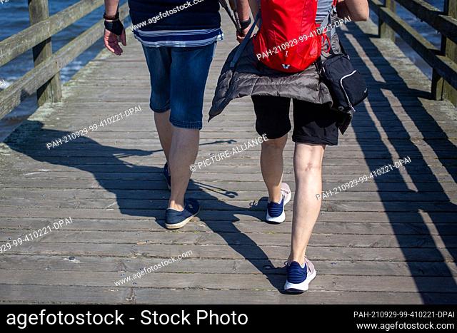 PRODUCTION - 28 September 2021, Mecklenburg-Western Pomerania, Ahlbeck: A couple walks along the pier on the beach of the Baltic resort of Ahlbeck on the island...