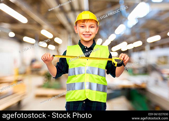 boy in construction helmet and vest with ruler
