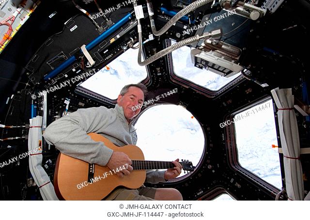 NASA astronaut Stephen Robinson, STS-130 mission specialist, plays a guitar in the Cupola of the International Space Station while space shuttle Endeavour...