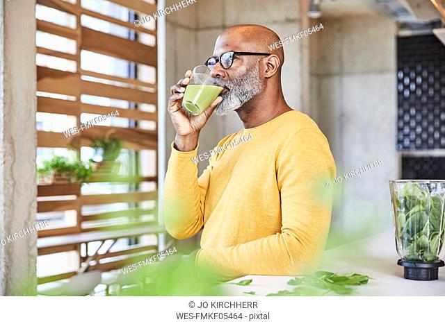 Mature businessman in office drinking a smoothie
